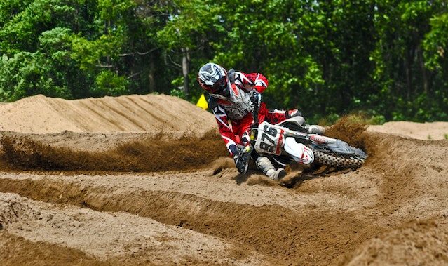 Motorcycle rider falling in the sand while wearing full motocross protective gear.