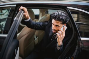 Lawyer handling California Uber accident case, speaking on phone while exiting vehicle.