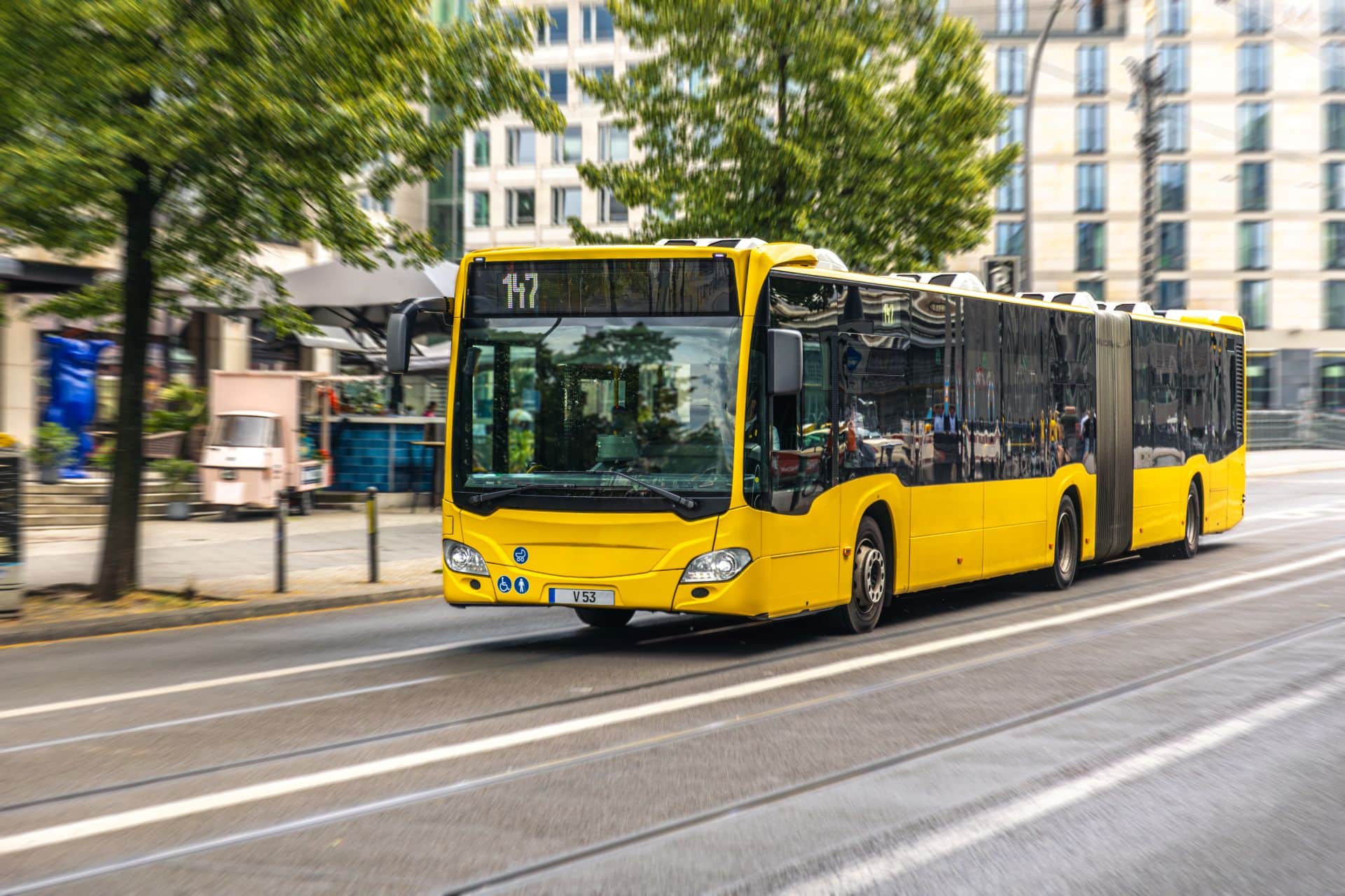 Yellow city bus driving on a San Diego street, illustrative of public transit and school bus accident lawsuits handled by Babaians Law Firm.