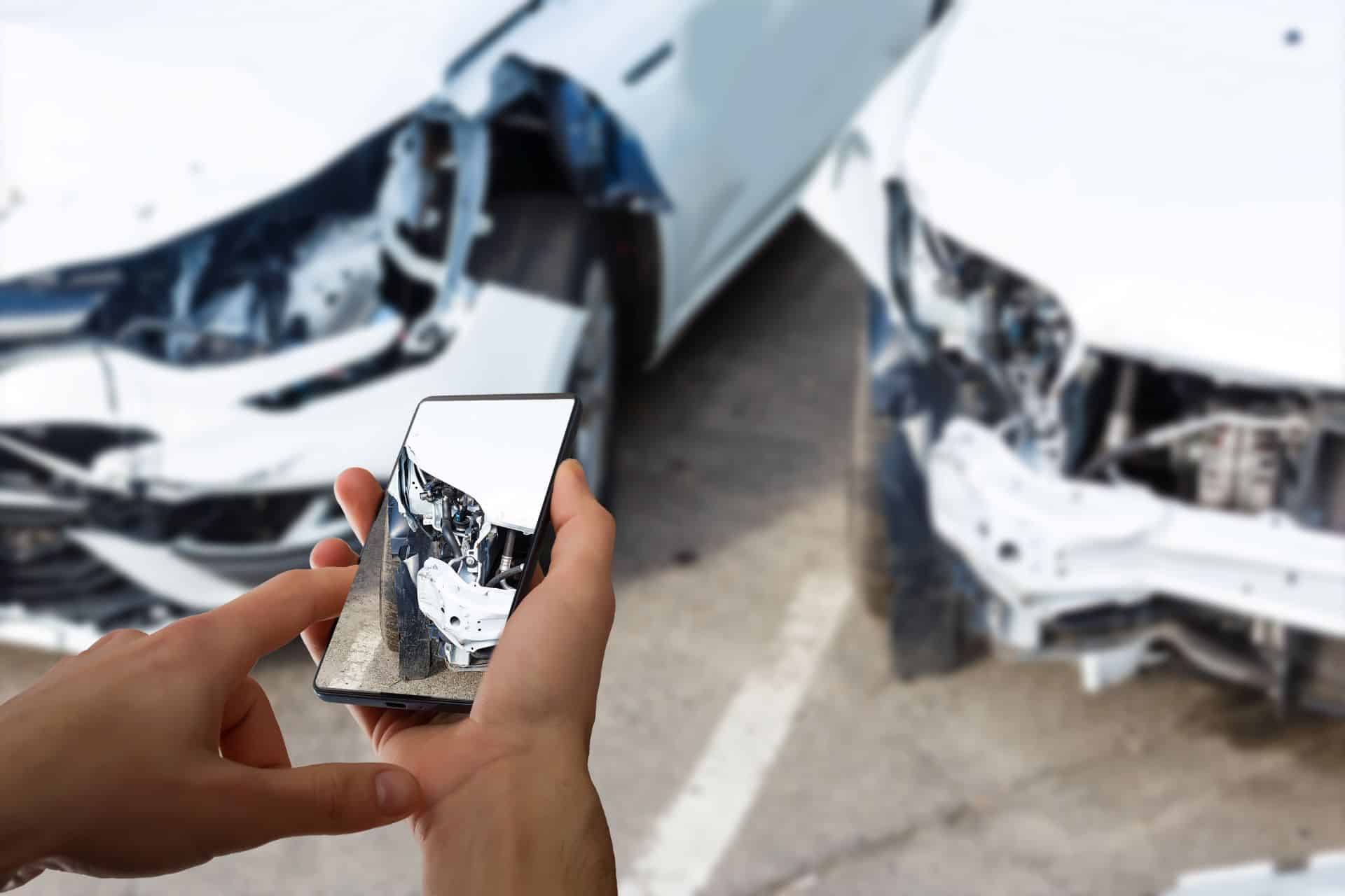 Person taking photos of a damaged vehicle at an accident scene, illustrating evidence collection for an Anaheim car accident injury claim.