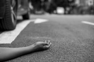 Accident victim on the ground beside a vehicle following a severe car crash, illustrating a Santa Ana car accident injury and wrongful death case.