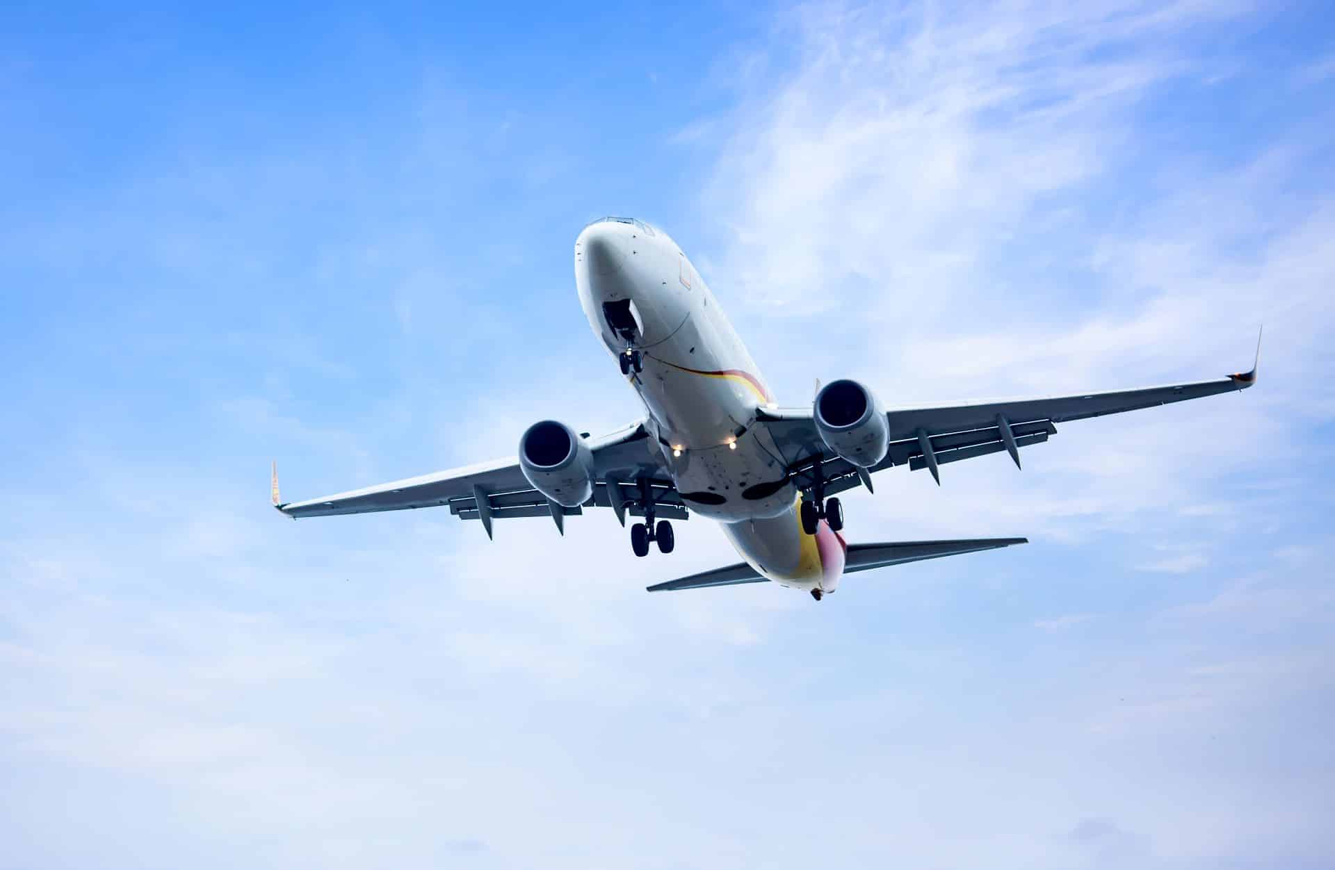 Large passenger plane flying overhead in a blue sky, a common aircraft involved in San Diego aviation and charter flight injury claims.