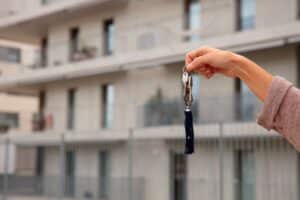 lose-up of a hand holding keys outdoors near an apartment complex, a setting for San Diego landlord negligence and injury lawsuits.