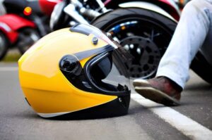A motorcycle helmet resting beside a crashed bike highlights the severe injuries riders can suffer in serious motorcycle accidents, including traumatic brain injuries, spinal cord damage, and life-altering physical trauma.