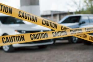 Driver reporting a car accident by phone while inspecting vehicle damage, highlighting the importance of a police report for a car accident claim.