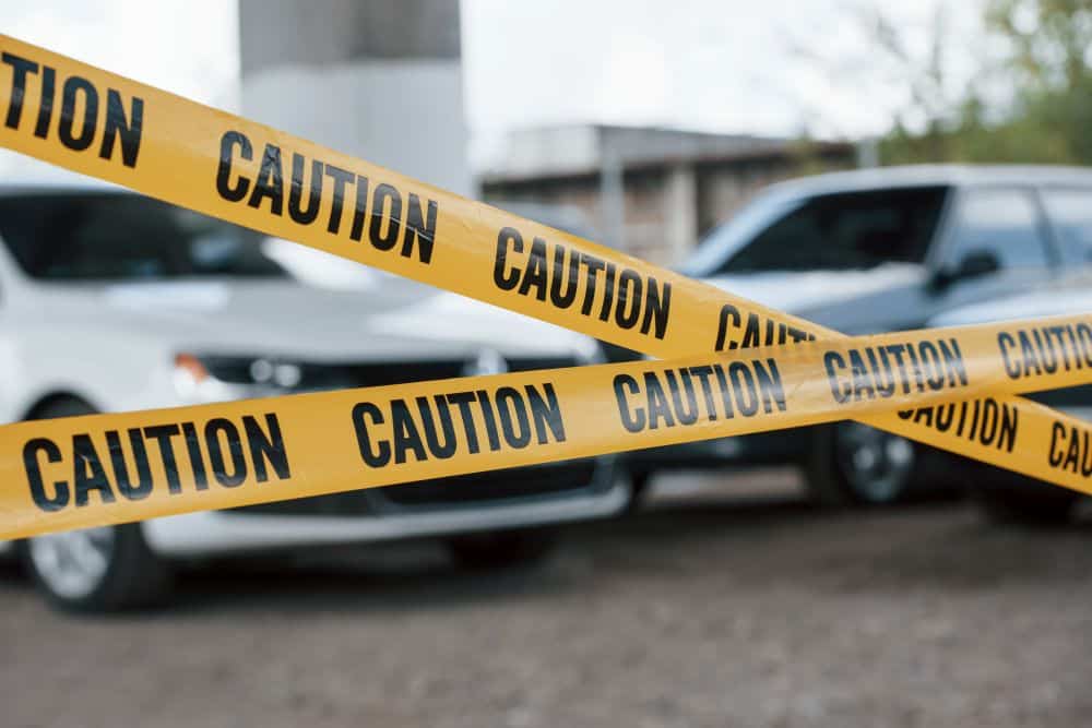 Driver reporting a car accident by phone while inspecting vehicle damage, highlighting the importance of a police report for a car accident claim.
