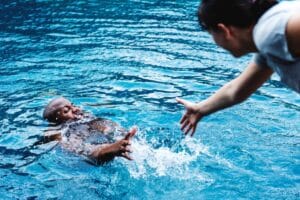 Emergency responders assisting a drowning victim beside a residential swimming pool, illustrating swimming pool drowning liability and premises liability claims in California.